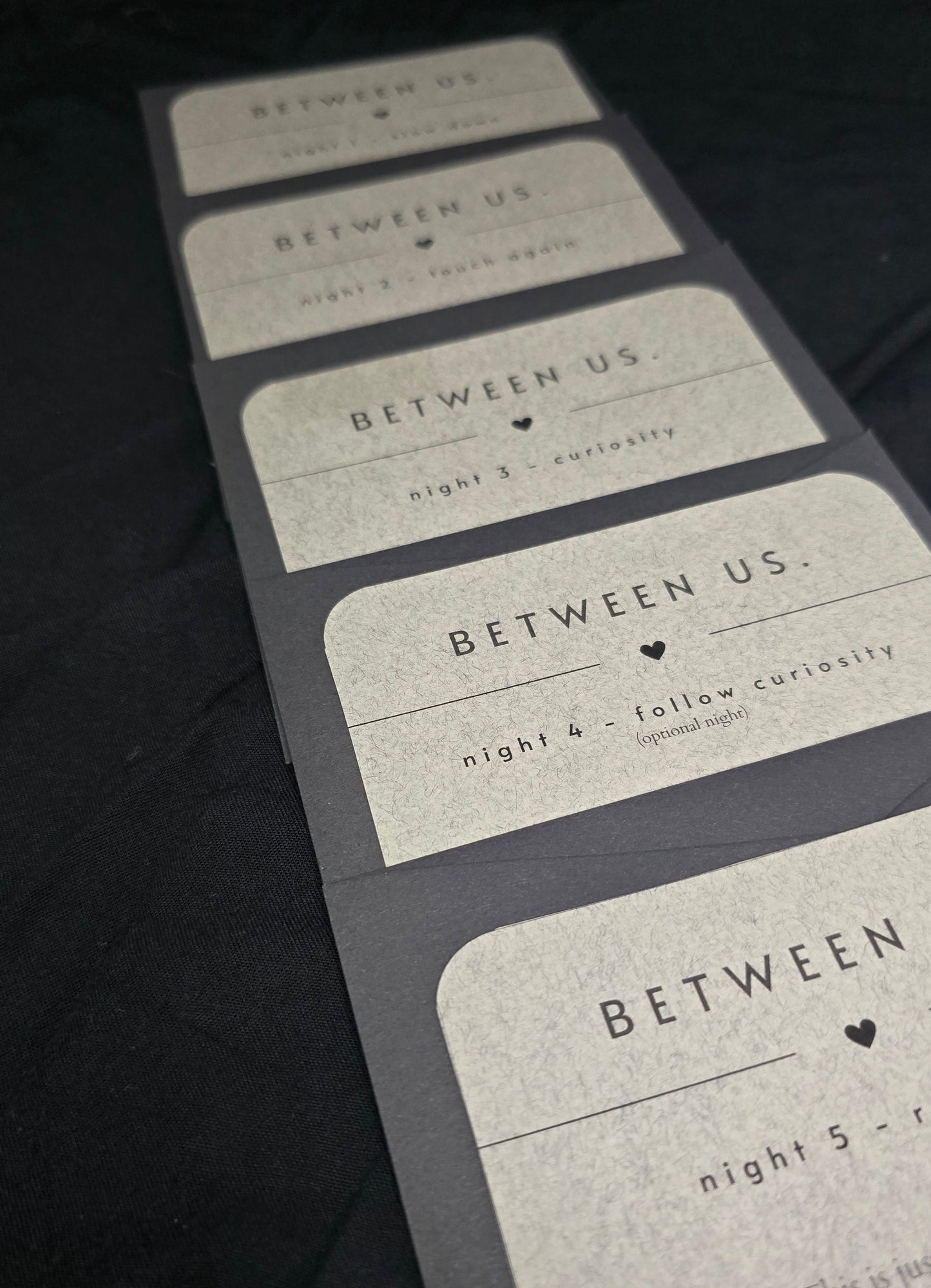 Close-up of 'BETWEEN US' book with textured pages on a dark surface